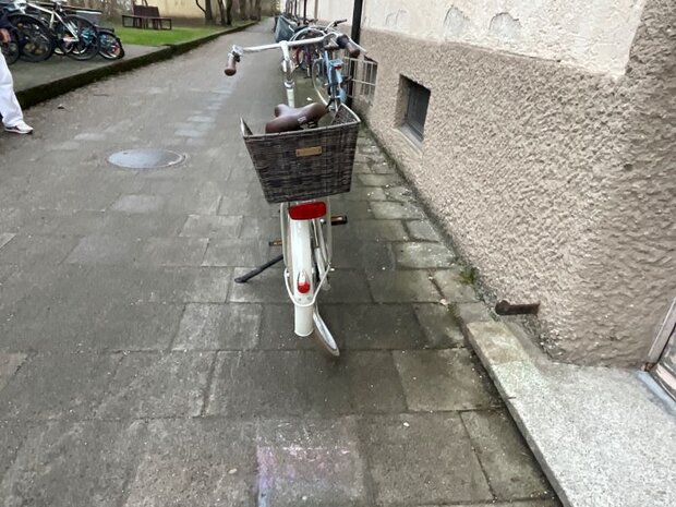 Unfallbeschädigtes weißes Citybike mit Korbschäden in München.